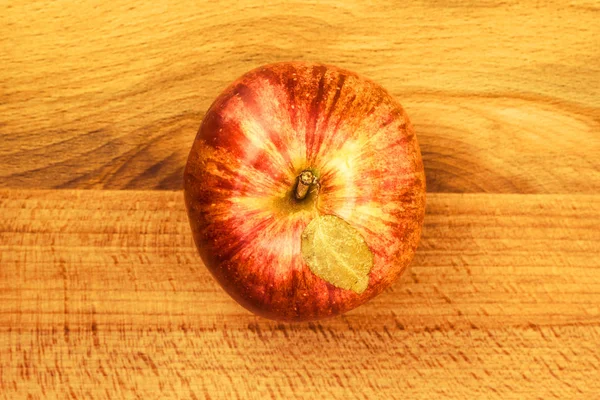 Fruit of a red apple with leaves on a wooden background — Stock Photo, Image