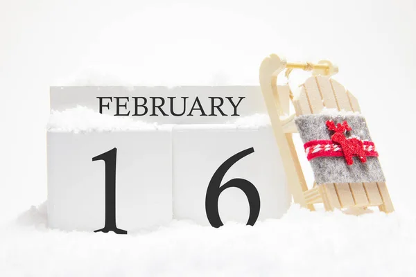 Calendario in legno per il 16 febbraio del mese invernale. I simboli dell'inverno sono neve e slitta. Concetto di vacanze, vacanze e divertimento invernale . — Foto Stock