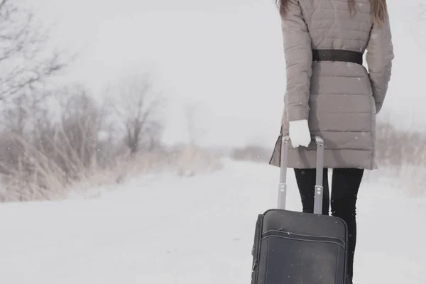 Dziewczyna podróżuje z walizką. Zimowa droga i młoda dziewczyna. — Zdjęcie stockowe