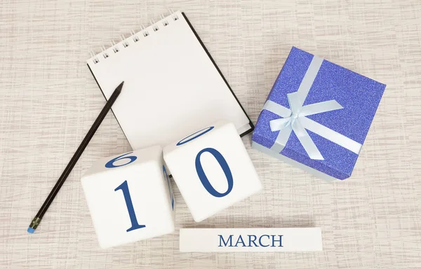Calendar with trendy blue text and numbers for March 10 and a gift in a box. — Stock Photo, Image