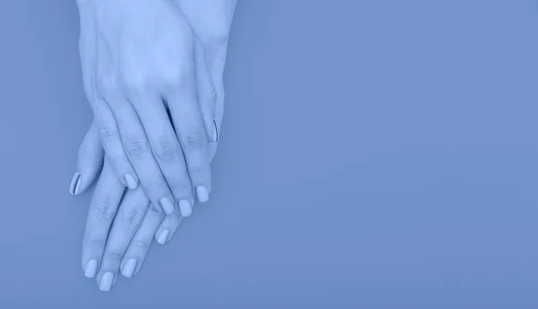 Elegante manicure femminile alla moda. Belle mani di giovane donna su sfondo giallo. Primo piano, tonica alla moda classico colore blu dell'anno 2020 — Foto Stock