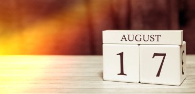 Calendar reminder event concept. Wooden cubes with numbers and month on August 17 with sunlight. clipart
