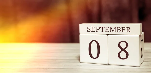 Calendario recordatorio concepto de evento. Cubos de madera con números y mes el 8 de septiembre con luz solar . — Foto de Stock