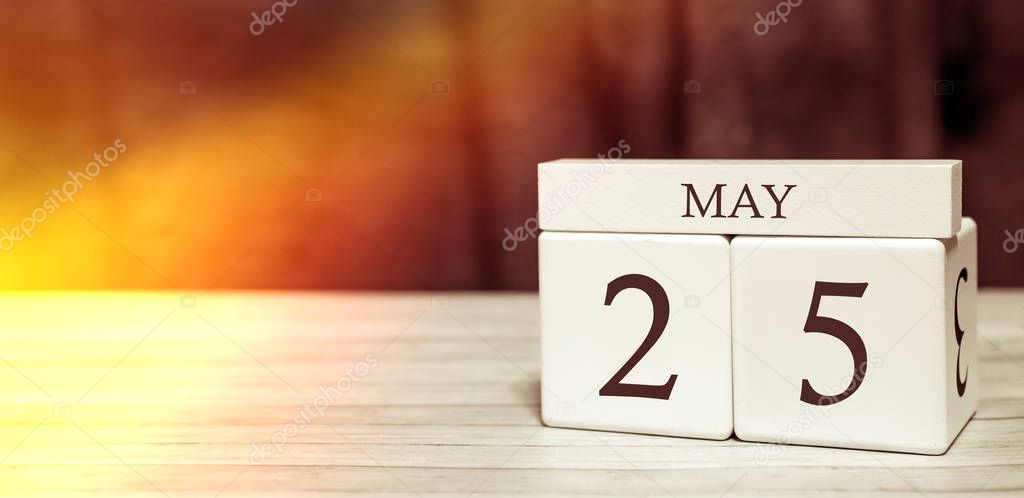 Calendar reminder event concept. Wooden cubes with numbers and month on May 25 with sunlight.