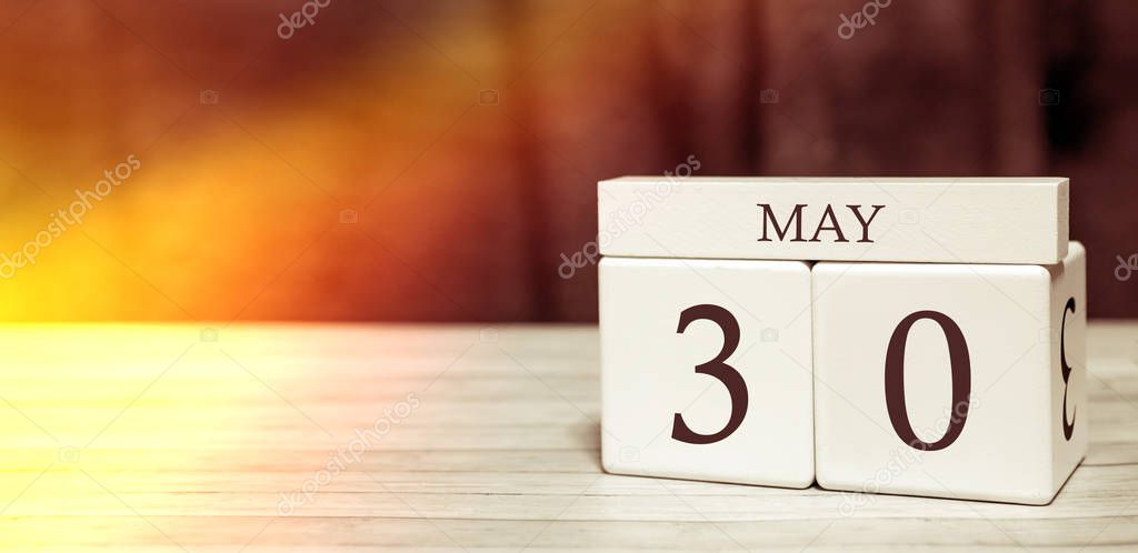 Calendar reminder event concept. Wooden cubes with numbers and month on May 30 with sunlight.