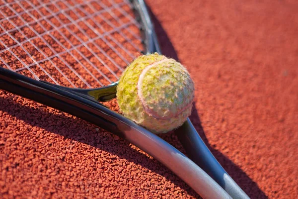 Single tennis racket on a orange sand court with a tennis ball close-up — Stock Photo, Image