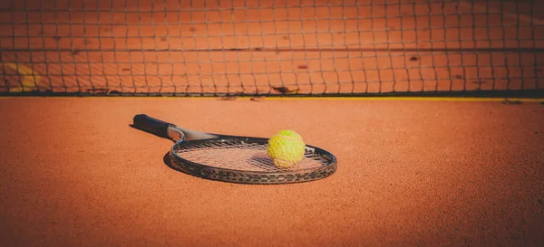Tennis racket and yellow ball on hard orange court — Stock Photo, Image