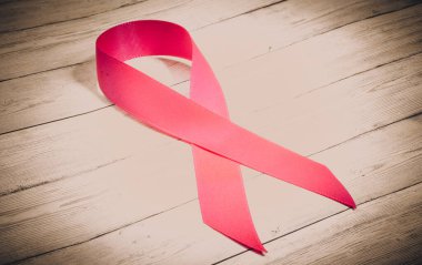 Göğüs kanserinin sembolü olarak ahşap bir arka planda pembe kurdele, kanserle mücadelenin bir işareti.