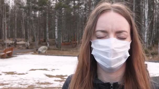 Young girl in a medical mask, health protection against viruses, bacteria and coronavirus. Against the background of a gloomy forest. — Stock Video