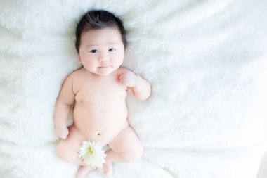 Şirin bebek çocuk stüdyoda ateş ediyor. Bebek ve aile moda görüntüsü. Bebek güzel bir yumuşak beyaz halı üzerinde uzan. görüntü arka plan, duvar kağıdı, kopya alanı, nesneler, moda ve makale için.