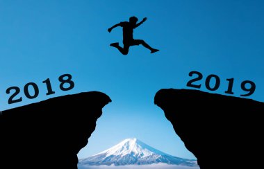 Genç bir adam hill siluet akşam renkli gökyüzü boşluğu üzerinde 2018 ve 2019 yılları arasında güneş üzerinde ve üzerinden atlamak. mutlu yeni yıl 2018.