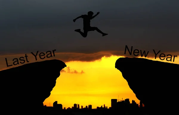 A young man jump between last year and new year  over the sun and through on the gap of hill silhouette evening colorful sky. happy new year 2018.