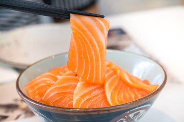 Somon dilimi yakından chopsticks tarafından aldı. somon taze somon tarafından tepesinde wasabi ve soya sosu, donburi pilav ile servis. görüntü için arka plan, kopyalama alanı, süslemeleri ve menü listesi.