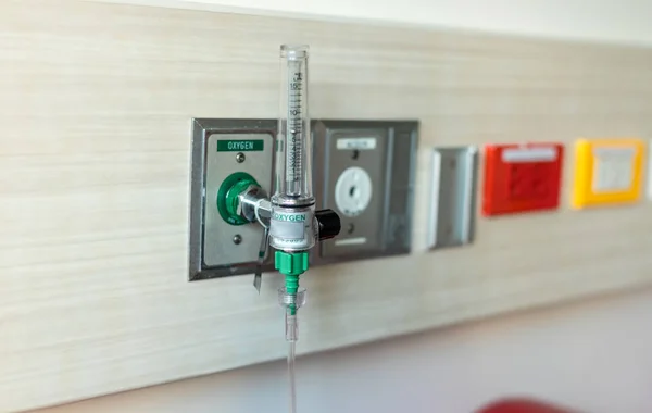 Oxygen flow meter plugged in the green outlet on hospital wall, Medical equipment. Oxygen for patients in the wall. Oxygen Gas Pipeline connection Inside Hospital ICU Room.