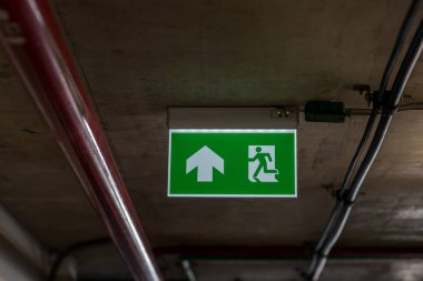 Kaçış yolunu gösteren yeşil acil çıkış işareti. Binadaki yangın çıkışı..