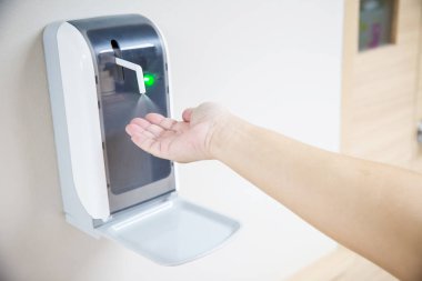 Hands under the automatic alcohol dispenser. Infection and hospitably concept. save and clean in the public area. 