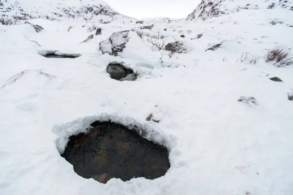 Lake on wintertime with broken ice. Crack broke the thick ice. A frozen hole in the ice. Winter river. Frozen lake covered in snow. Huge hole in the ice surface.