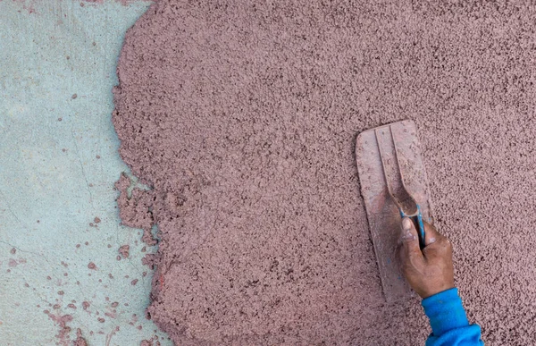 Worker plastering cement at wall or floor for building house. Construction worker plastering and smoothing concrete wall with cement. Plaster facade for wall decoration. Applying plastering mortar.