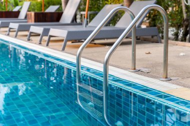 Yüzme havuzuna inmek için merdiven paslanmaz tırabzanlar. Tırabzanlı yüzme havuzu. Yüzme havuzu merdiveni. Yatay çekim.