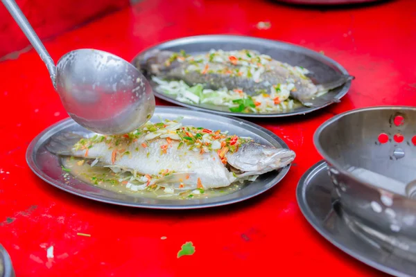 Steamed sea bass fish with lemon, Thai famous local food served on fish shape plate. Thai recommend menu for tourist. Steamed fish with herb and lemon, topped with spicy sour sauce. PLA NERNG MANAW.