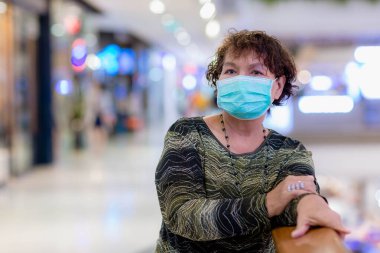 Kraliyet virüsüne karşı korunmak için Covid-19 maskeli yaşlı Asyalı kadın. Kirli hava dumanı yüzünden koruyucu maskeli Asyalı yaşlı kadın, PM2.5. Coronavirus yaşlı kadın ameliyat maskesiyle yürüyor.