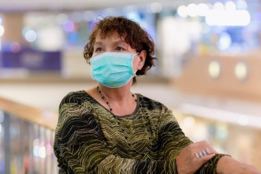 Kraliyet virüsüne karşı korunmak için Covid-19 maskeli yaşlı Asyalı kadın. Kirli hava dumanı yüzünden koruyucu maskeli Asyalı yaşlı kadın, PM2.5. Coronavirus yaşlı kadın ameliyat maskesiyle yürüyor.