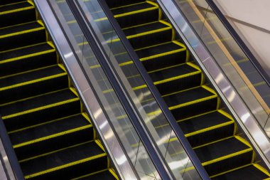 Alışveriş merkezinde modern yürüyen merdiven. Havaalanındaki yürüyen merdivende hiç insan yok. Simetride yükselen ve inen yürüyen merdivenler. 