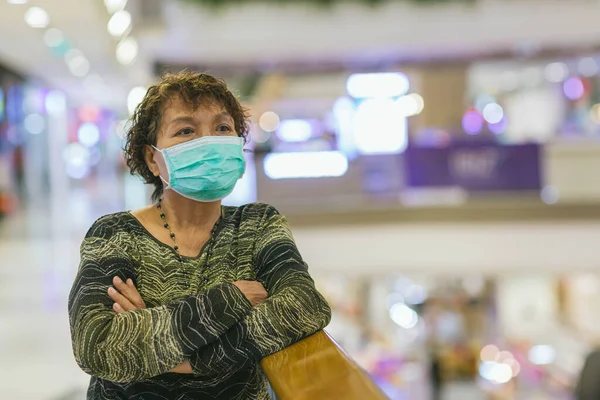 Old asian woman in a mask for COVID-19, for protection against the crown virus. Asian senior woman with protective mask because dirty air smog, PM2.5. Coronavirus old woman walking with surgical mask