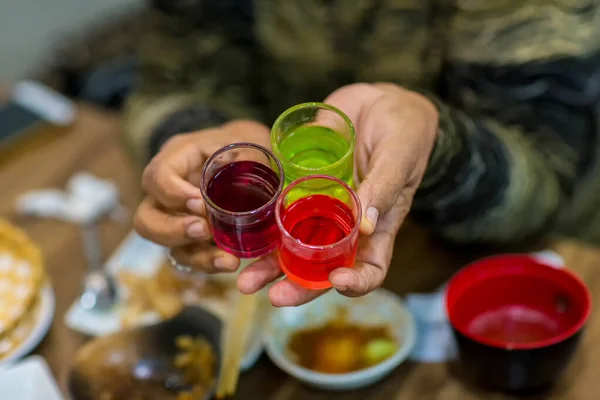 Dessert glass cup of colorful jelly served on hand woman. colored fruit jelly in glass cup . Eating colorful striped jelly or jello on hand. Multi Color fruit jelly in the glass cups.