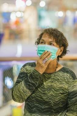 Kraliyet virüsüne karşı korunmak için Covid-19 maskeli yaşlı Asyalı kadın. Kirli hava dumanı yüzünden koruyucu maskeli Asyalı yaşlı kadın, PM2.5. Coronavirus yaşlı kadın ameliyat maskesiyle yürüyor.