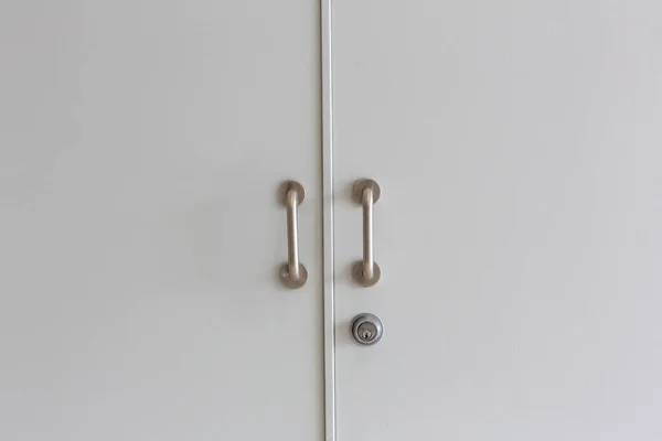 Gray color door is close. Wood door with metal and aluminum handles close up