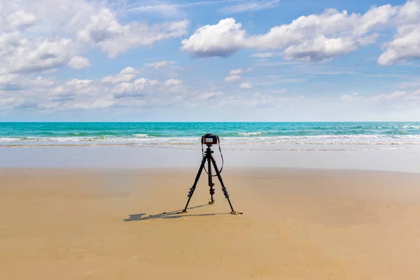 Digital professional camera stand on tripod photographing sea.