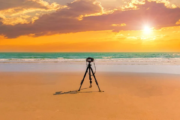 Digital professional camera stand on tripod photographing sea. Twilight sky background. Colorful Sunset sky and cloud.vivid sky in twilight time background.Fiery orange sunset sky. Beautiful