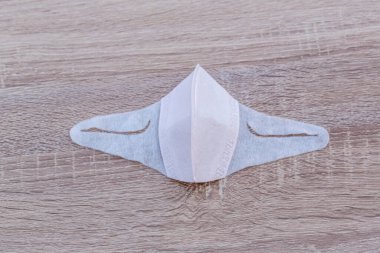 Ahşap masada koruyucu yüz maskesi. Ağız ve burnu örtmek için tipik 3 katlı cerrahi maske. Bakterilerin prosedür maskesi. Koruma konsepti. Plastik kulaklıklı cerrahi maske. covid 19