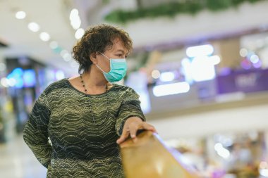 Kraliyet virüsüne karşı korunmak için Covid-19 maskeli yaşlı Asyalı kadın. Kirli hava dumanı yüzünden koruyucu maskeli Asyalı yaşlı kadın, PM2.5. Coronavirus yaşlı kadın ameliyat maskesiyle yürüyor.