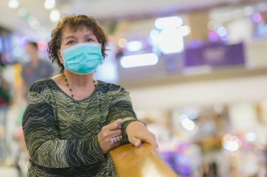 Kraliyet virüsüne karşı korunmak için Covid-19 maskeli yaşlı Asyalı kadın. Kirli hava dumanı yüzünden koruyucu maskeli Asyalı yaşlı kadın, PM2.5. Coronavirus yaşlı kadın ameliyat maskesiyle yürüyor.