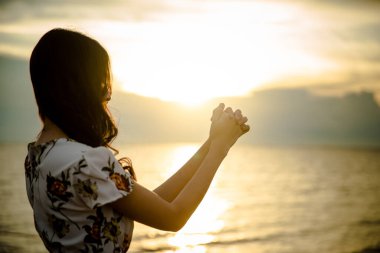 Gün batımında kumsalda sırt çantalı bir kadın