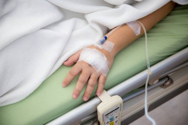 Kadın eli bir hastanın kolunu tutuyor.