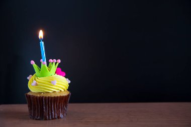birthday cupcake with burning candle on table