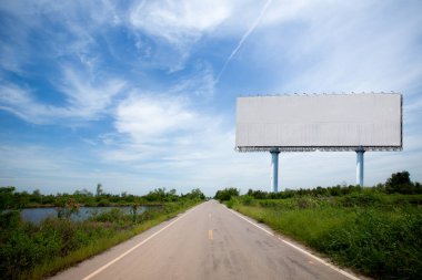 Mavi gökyüzü arka planında boş ilan panosu olan boş yol