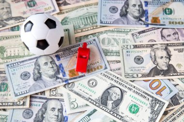 Stadyumun arka planında Amerikan futbolu topu ve doları var.