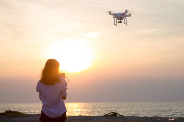 young woman with drone flying on the beach