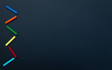 Siyah arka planda renkli tebeşir kalemleri. Üst Manzara. Boşluğu kopyala.