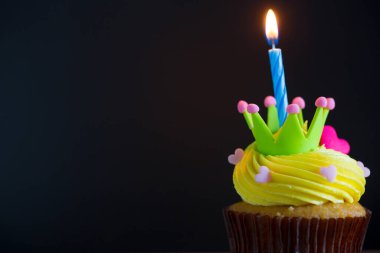 birthday cupcake with burning candle on a dark background