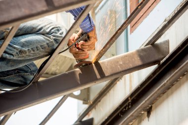 Matkap ve metal boruyla çalışan bir işçi.