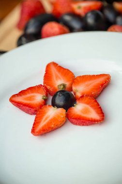 Beyaz bir tabakta taze çilek ve çilek.