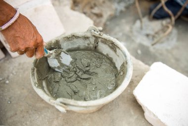 İşçi seramik fayansla kil tenceresi yapıyor.