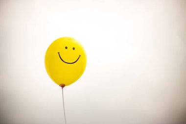 Beyaz arka planda gülüşü olan sarı balon.