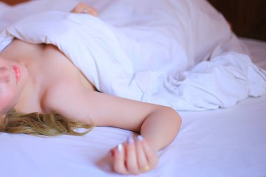 Güzel genç bir kadın yatakta yatıyor.