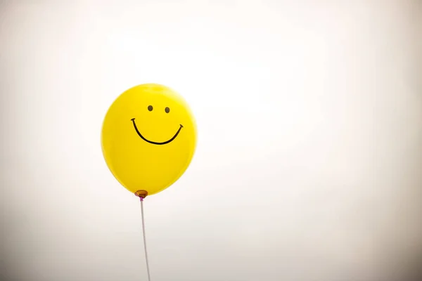 yellow balloon with a smile on a white background